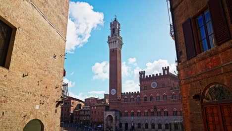 Walking-towards-the-Piazza-del-Campo-with-the-Tower-of-Mangia-in-the-background,-Siena,-Italy