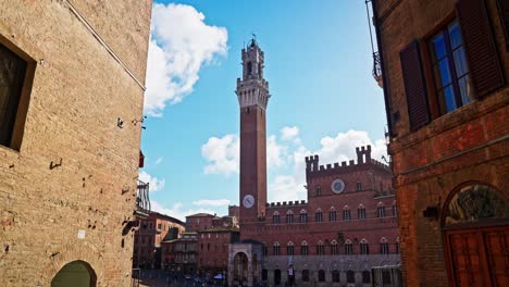 Caminando-Hacia-La-Piazza-Del-Campo-Con-La-Torre-De-Mangia-Al-Fondo,-Siena,-Italia