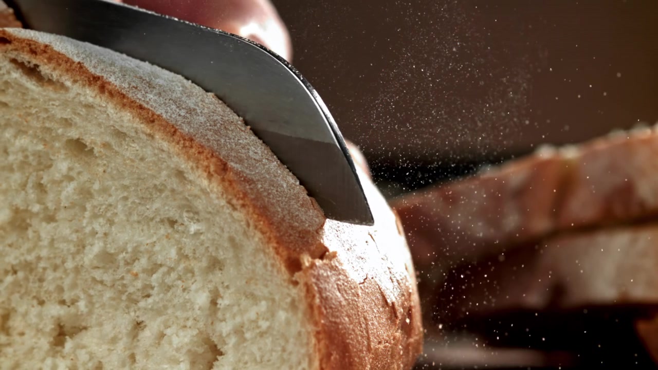 Close-up of a Serrated Knife Slicing Fresh White Bread in Slow Motion