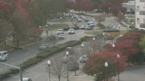 high angle of a city intersection, with autumn trees, streetlights, and multiple cars passing