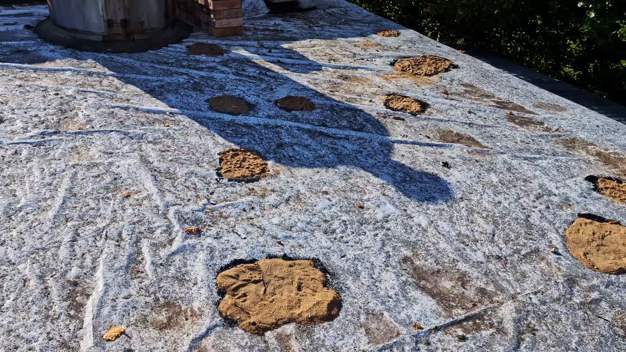 Processo di riparazione e rattoppo del tetto con mattoni e un vecchio camino sull'esterno della casa. Superficie del tetto in fase di ristrutturazione, operai che riparano toppe e un vecchio camino in metallo. Manutenzione dell'edificio
