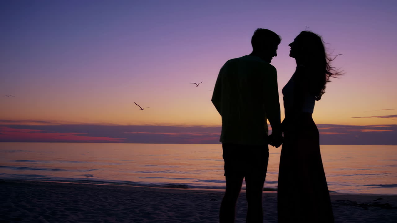 해가 지는 해변에 있는 커플