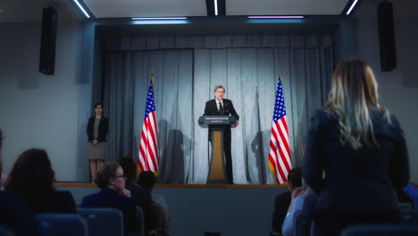 president of usa answers journalists questions and gives interview. confident american republican politician delivers successful speech to supporters at press conference. backdrop with american flags.