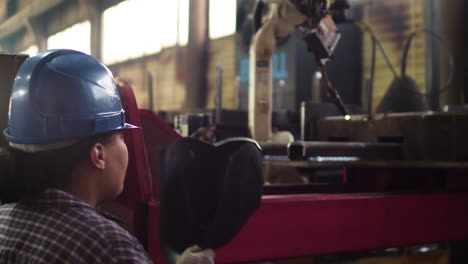 worker with welding helmet in factory