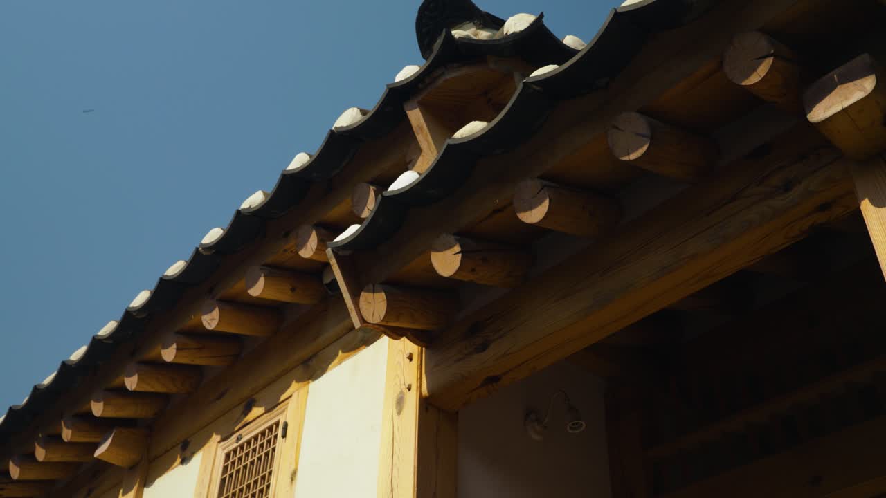 A close-up captures the intricate details of a traditional Korean house in Bukchon Hanok Village, showcasing its wooden structure and tiled roof - Low angle parallax shot