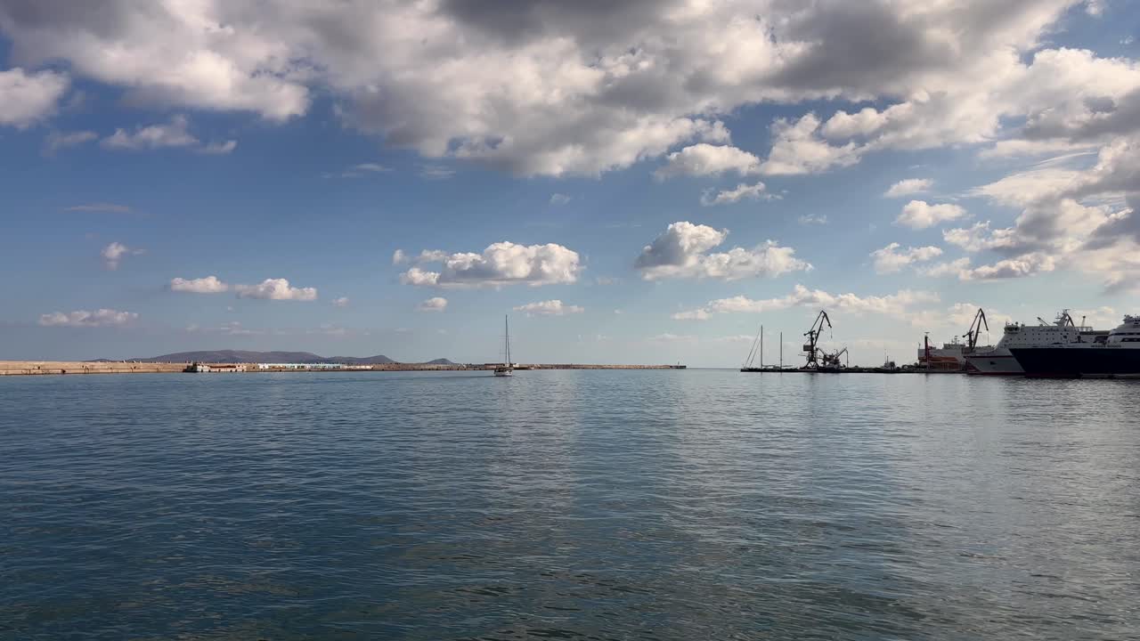 Calm Heraklion port with boats and cranes under cloudy sky, Crete, Greece