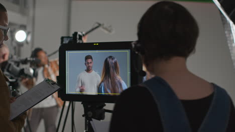 female film director and assistant watching actors shooting movie or video in studio on monitor 5