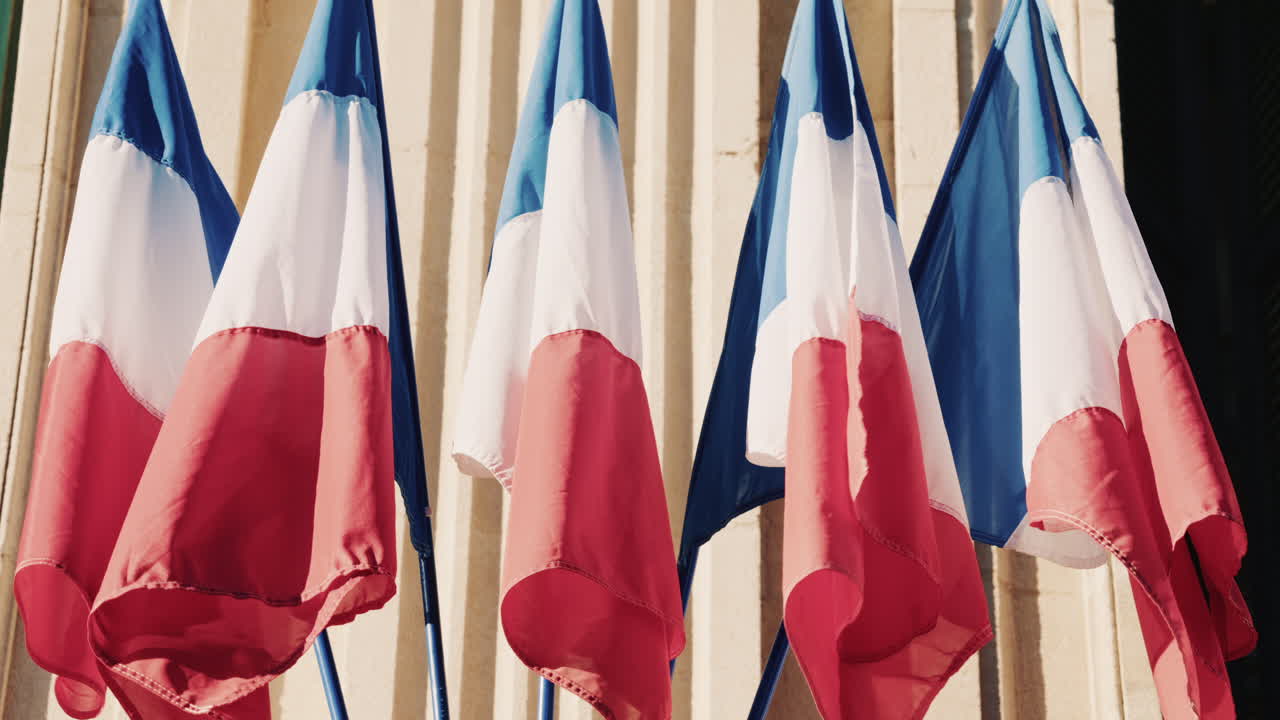 French national flags waving on the facade of a historic building in southern France