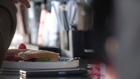 close up shot hand of people with breakfast sandwich meal on the table