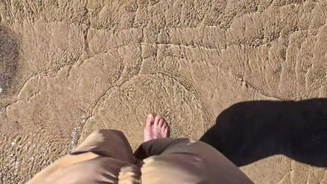 caucasian feet walk touching the water in white sand beach top down selfie pov