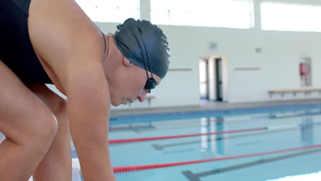 professional swimmer at the pool's edge, ready to dive