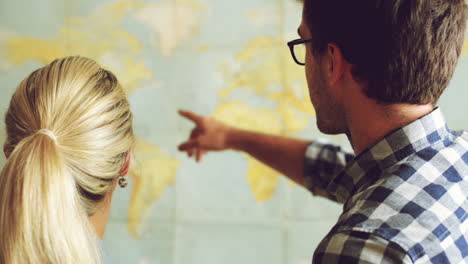 una joven pareja de turistas mirando el mapa del mundo