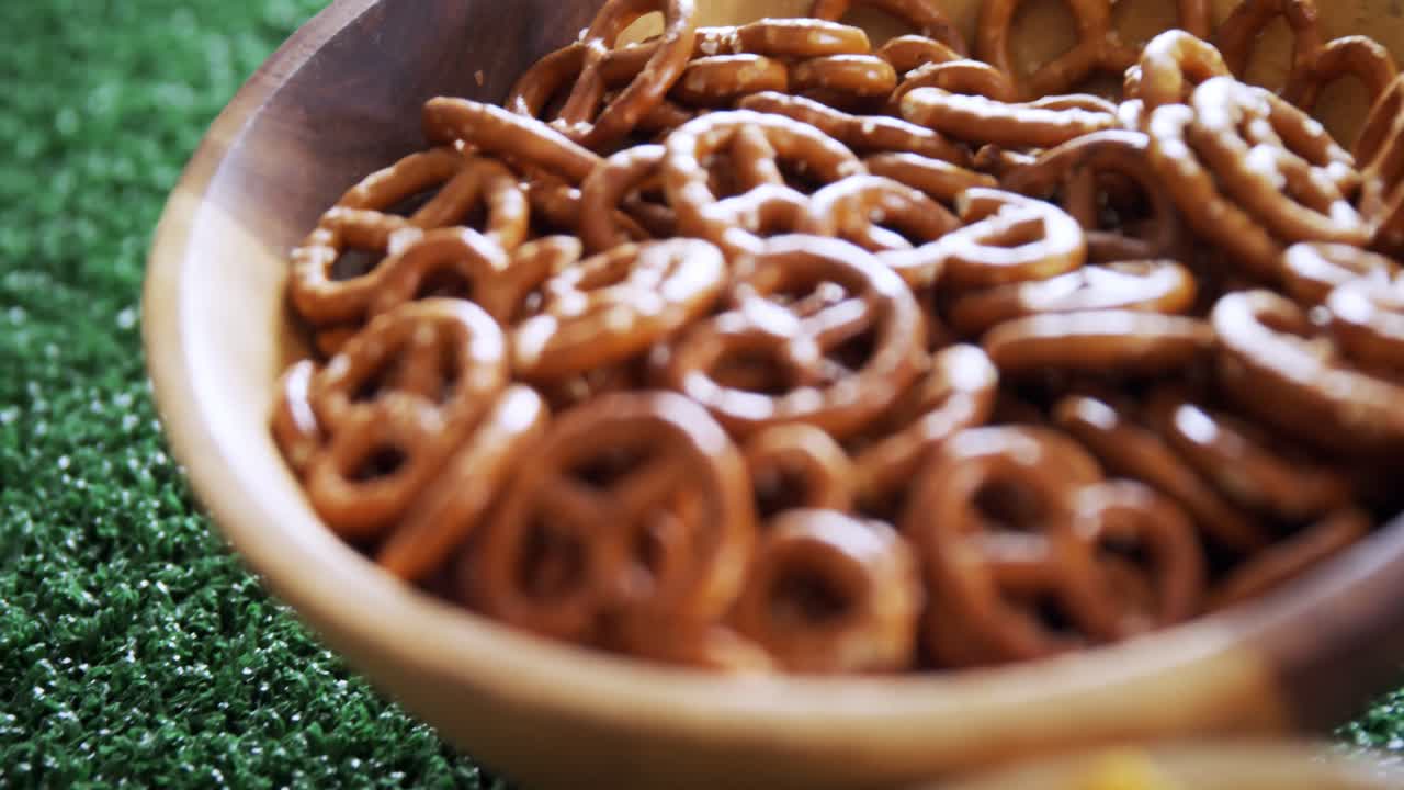 tazón de bocadillos, fútbol y un vaso de cerveza en una mesa de madera 4k