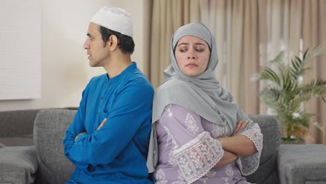 angry muslim couple sitting back to back