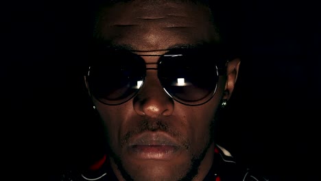 anonymous black man’s face with sunglasses starring, extreme close up