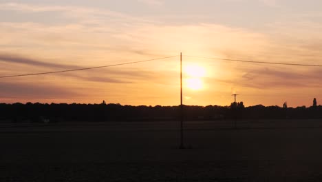 wide angle cinematic establishing shot of motorbike riding past in the distance with an orange sunset for a backdrop shot in prores raw