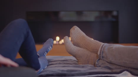 close up of couple relaxing and warming feet by fire at home