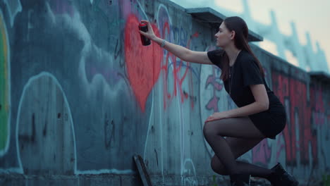 Chica-Pintando-El-Corazón-En-La-Pared-Con-Una-Botella-De-Spray.-Mujer-Dibujando-Graffiti-En-El-Edificio