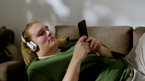 Mann-Mit-Kopfhörern,-Der-Zu-Hause-Soziale-Medien-überprüft