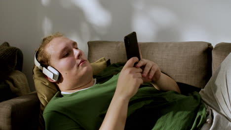 un tipo con auriculares revisando las redes sociales en casa.