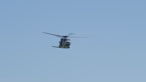 military helicopter ascends and pitches down, crew waving at display