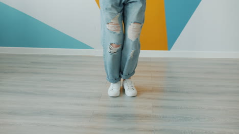 woman dancing in stylish ripped jeans and sneakers