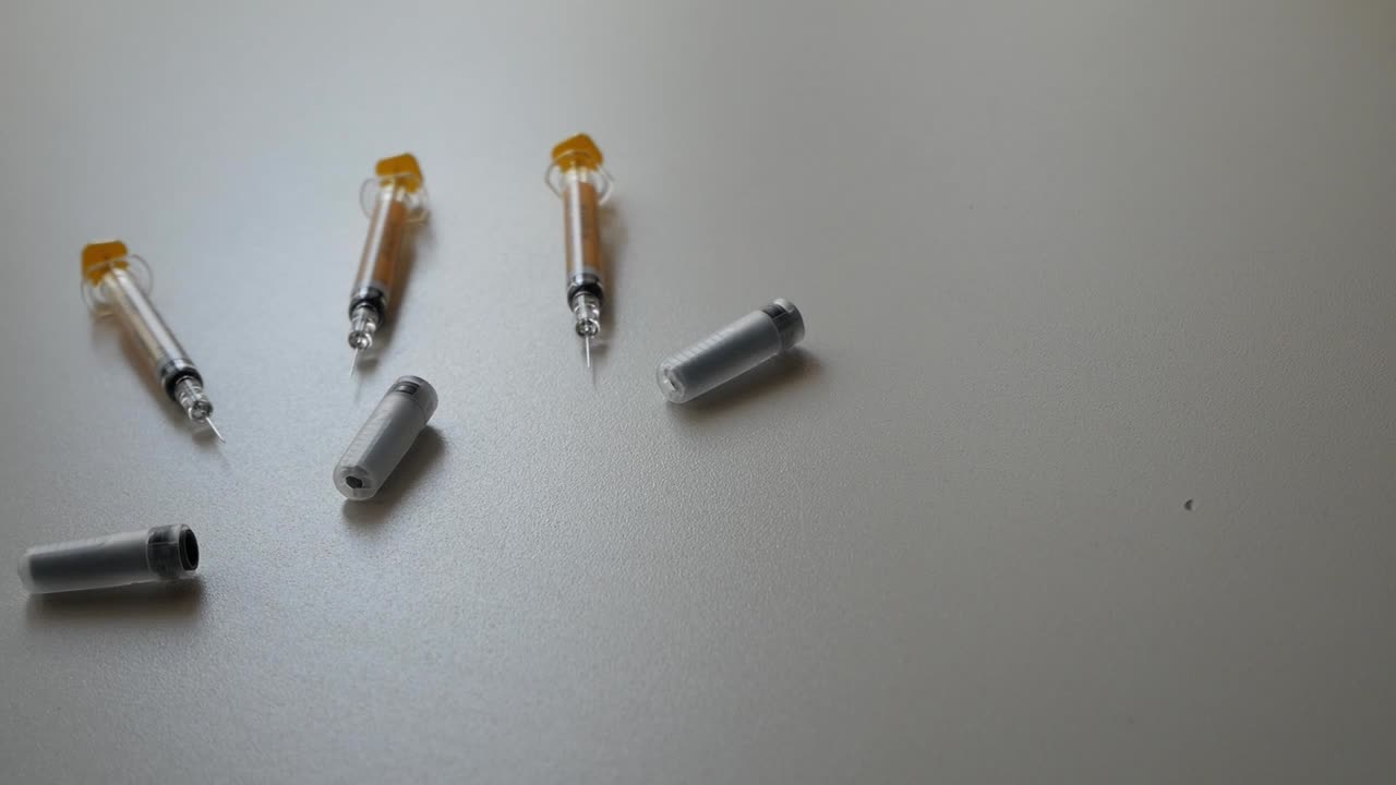 Syringes and container on white surface in dynamic lighting