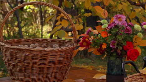 large wicker basket full of walnuts next to vase of flowers next to basket bowl of red pomegranates