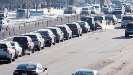 Lange-Autoschlange-Auf-Der-Linken-Abbiegespur,-In-Einer-Eisigen,-Einfarbigen-Winterstadt