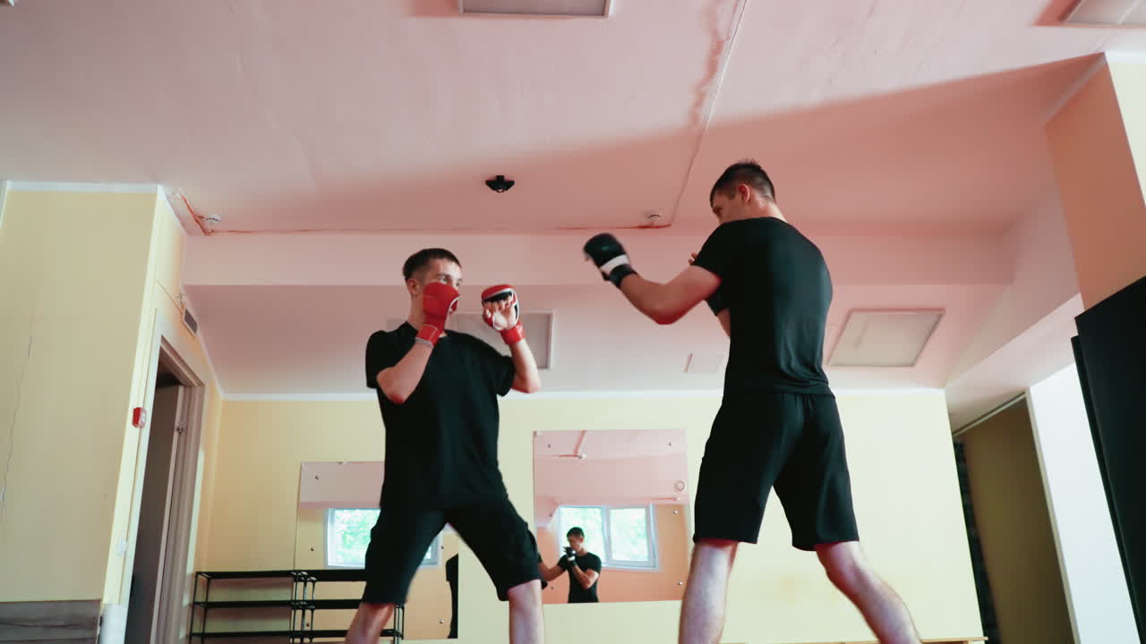 Fighters with gloves sparring in martial arts gym, throwing fast punches while opponent dodges under defensive stance, showcasing speed, agility, power, combat training during workout session