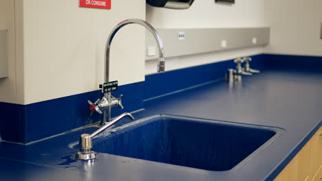 a college science biology professor washing his hands and turning off the water faucet after an experiment in his classroom lab