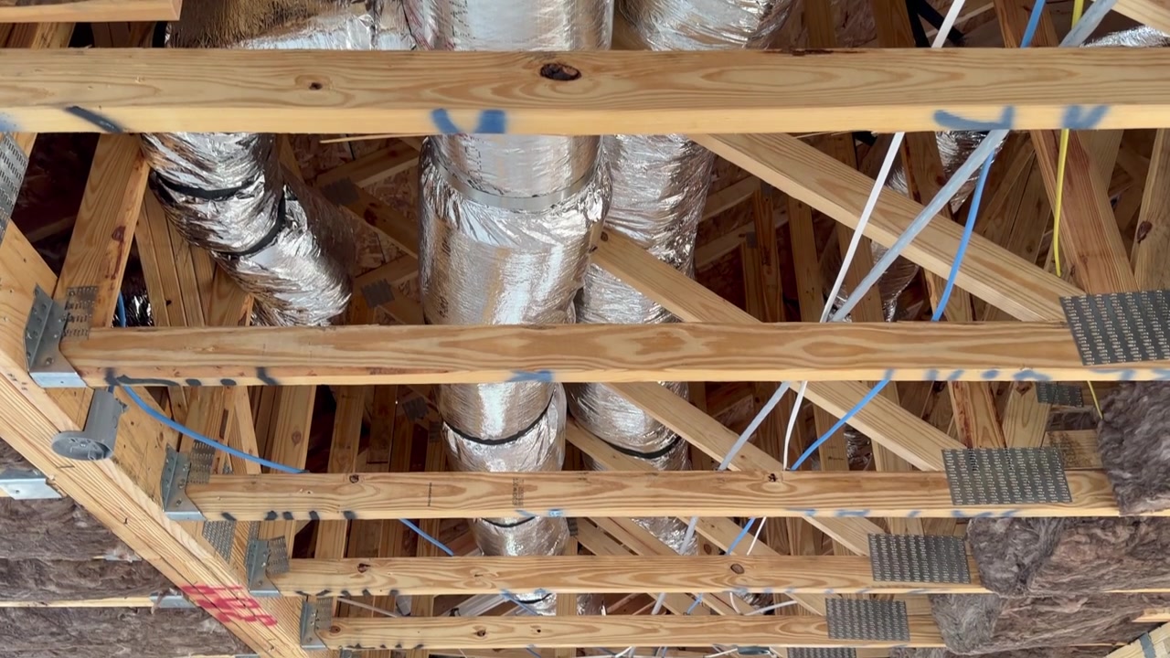 Innenansicht eines neuen Hauses nach der Installation der Lüftungsrohre und Elektroverkabelung, die hochwertige Handwerkskunst hervorhebt. Perfekt für Subunternehmerinspektionen und Immobilienentwicklungsprojekte.