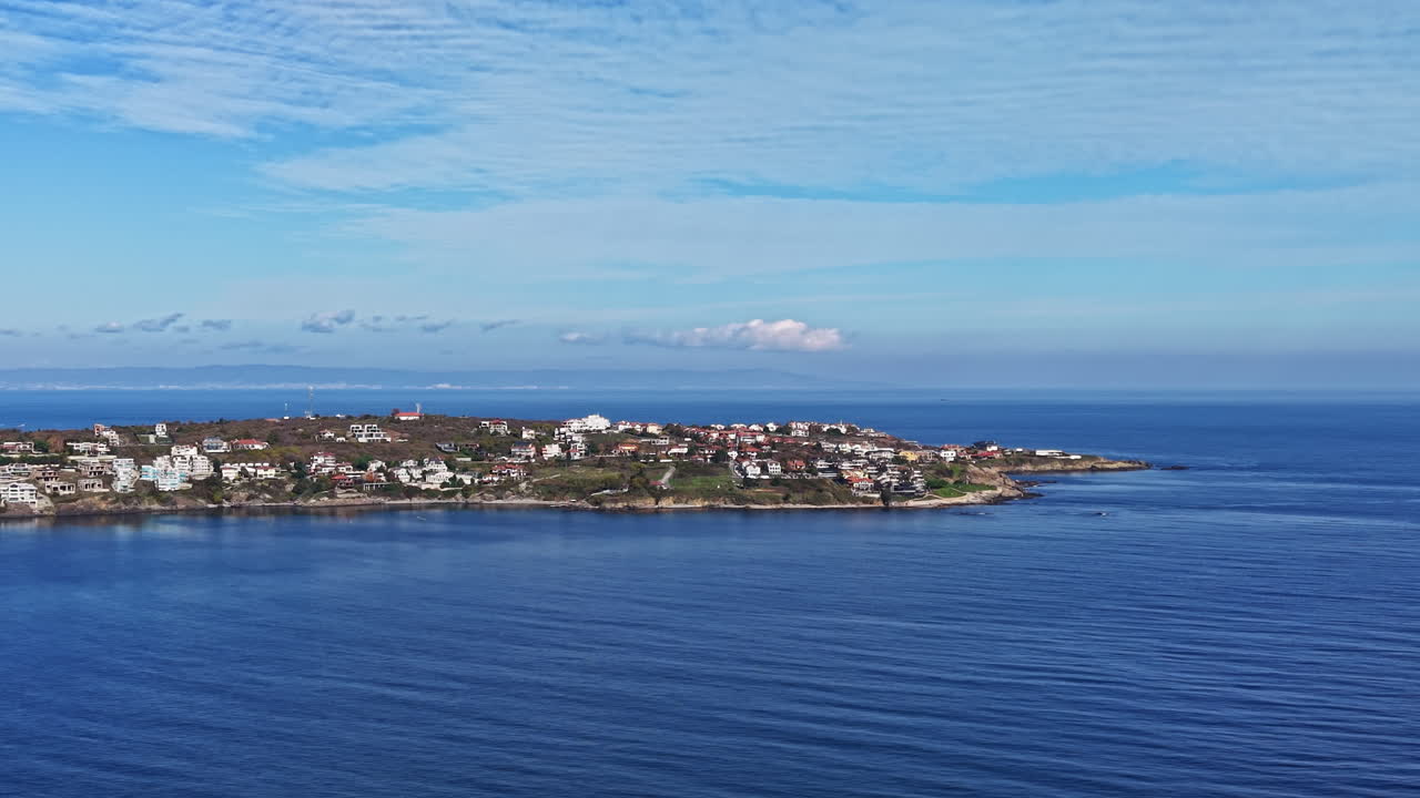 Vista costiera di acque tranquille e case incantevoli a mezzogiorno, che cattura l'essenza di una pacifica località marittima