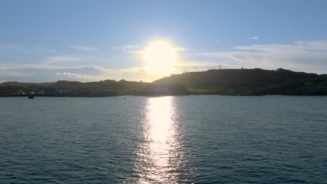 Drone-Sobrevolando-El-Paisaje-Marino-Con-Reflejos-De-Luz-Solar-Hacia-Cabo-Quejo,-Cantabria