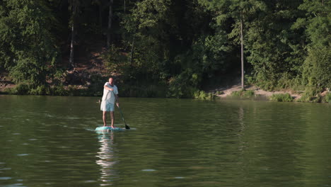 senior caucasian guy paddling paddleboard on pond or lake, front wide angle view