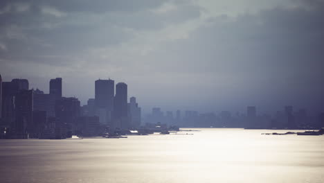 overcast skyline view of a bustling city by the tranquil water at dusk