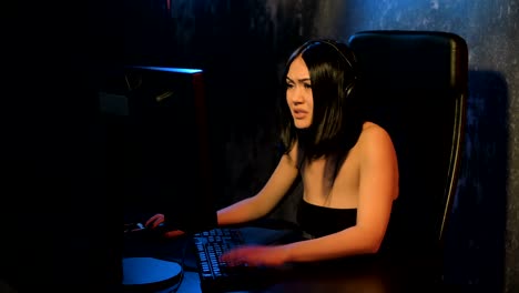 jugadora con auriculares y con ratón y teclado en las manos jugando juegos en red preparándose para participar en competiciones internacionales de deportes electrónicos