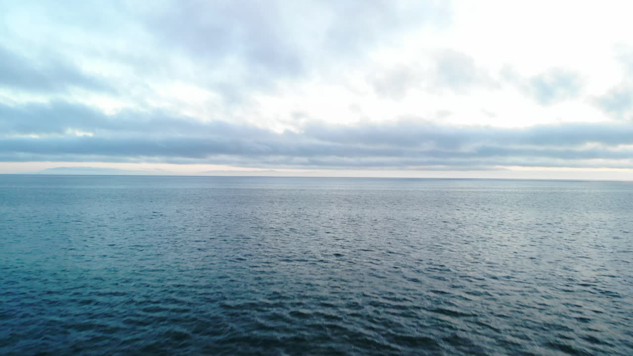 Luftfoto med drone, der flyver hurtigt og lavt over Stillehavets overflade, hvor bølgerne brager mod kysten i Ventura, Californien.
