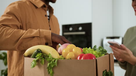 man receiving box of vegetables