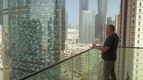 senior caucasian man taking a phone call on a balcony, abu dhabi city skyline in the background