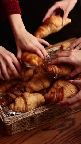 hands reaching for croissants in a basket