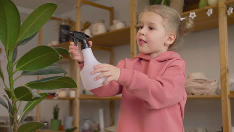 little girl spraying water on a plant at a table in a craft workshop