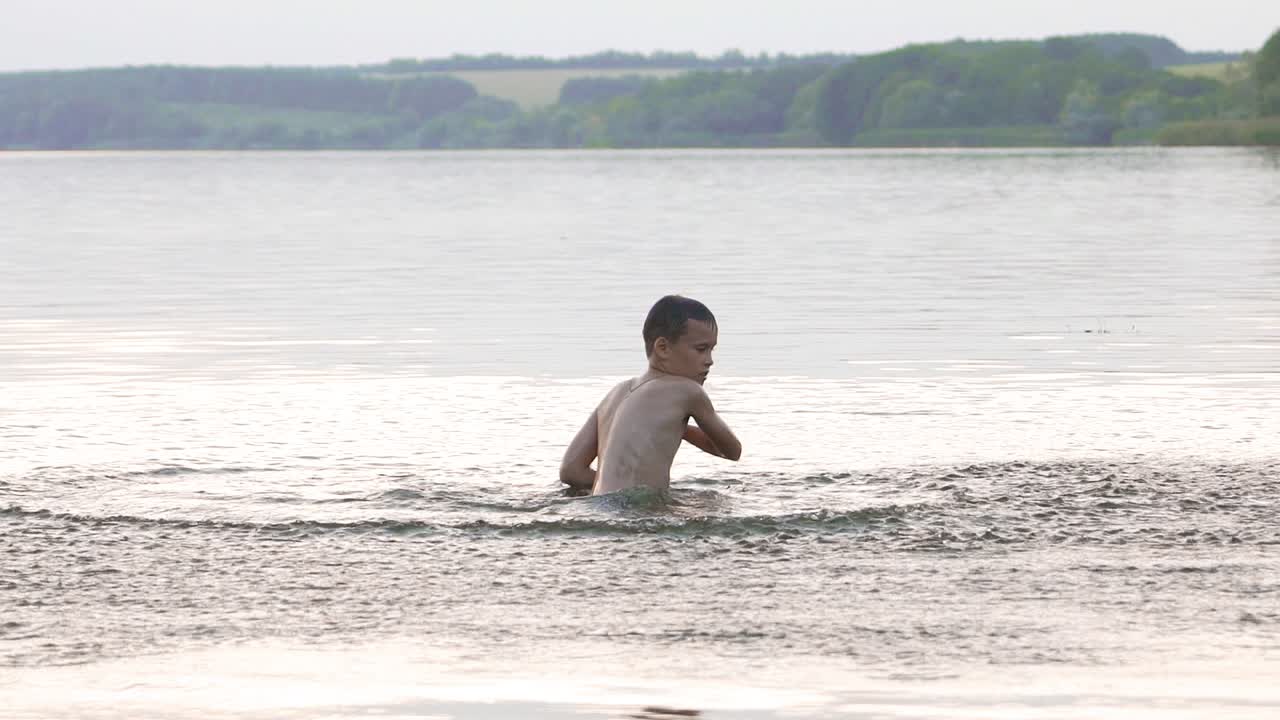 little kid play in water and making splash; child swim in lake or river and have fun with drops