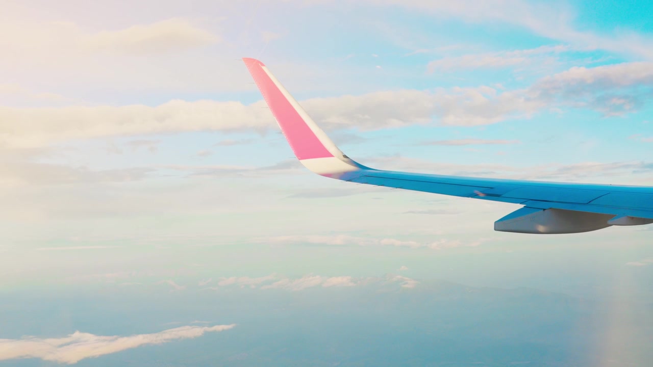 Asa de avião vista voando acima das nuvens, com céu parcialmente nublado. A cena captura a asa e o horizonte da perspectiva de um passageiro.