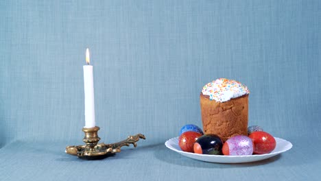 cámaras de llegada, arreglo de pascua, pascua en el plato blanco con huevos teñidos, cerca de la vela blanca ardiente