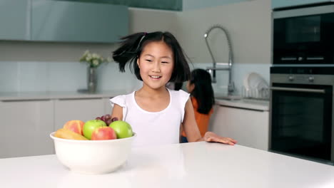 little girl taking apple out of bowl