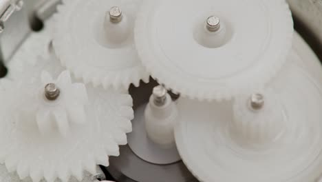 five plastic gears rotate in mutual mesh inside a small reduction gear