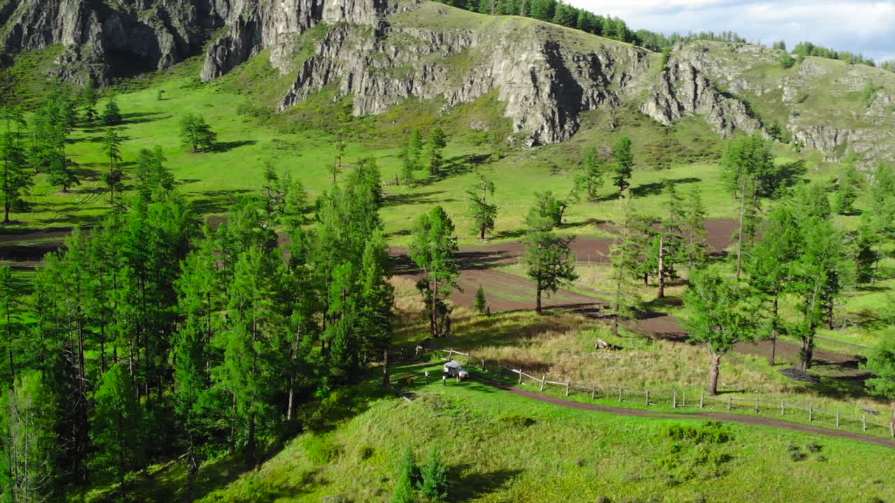 Aerial View of Lush Green Mountains and Forest with a Winding Path and Vehicle