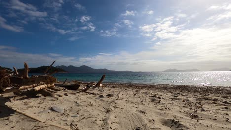 Time-lapse-of-logs-on-a-beach,-coast-of-Majorca,-sunny-day,-in-Balearic-islands,-Spain---Static-shot