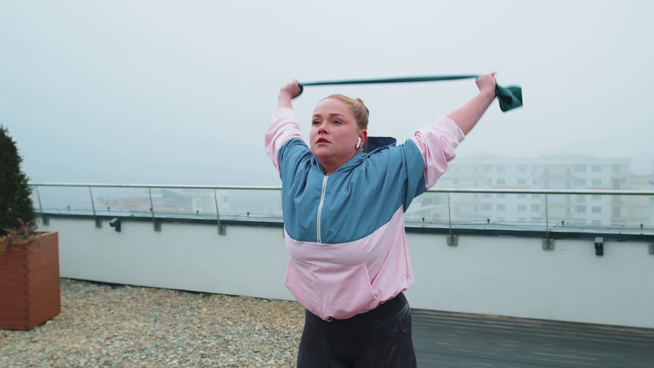 chica deportiva en ropa deportiva hace yoga estiramiento ejercicio usando banda de goma en el techo de la casa al aire libre